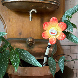 Pique décoratif pour plante avec tête de fleur en céramique aux pétales orange jaune et rouge et bouche avec des dents